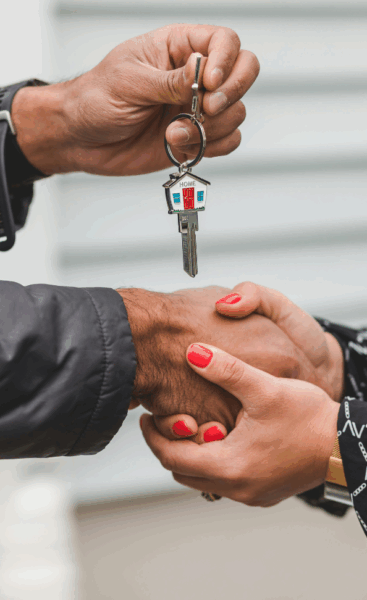 Remise de clés avec poignée de main entre deux personnes, symbole de confiance et d’acquisition immobilière